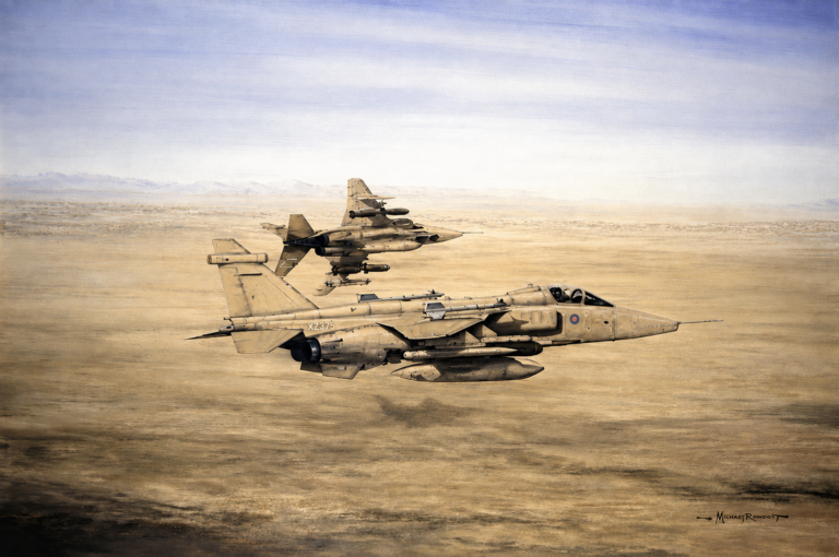 Two beige military fighter jets fly in formation over a flat desert, distant mountains on the horizon.