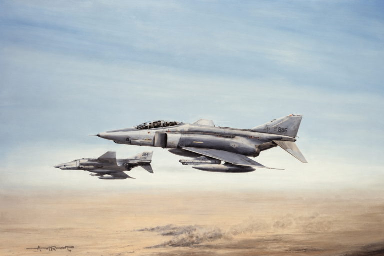 Two fighter jets fly in formation over a sandy desert landscape.