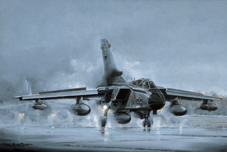 Gray military fighter jet on a wet runway in rain, water spraying from wheels as it lands, with external fuel tanks under wings.